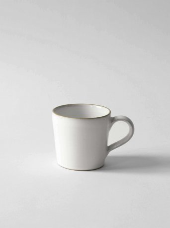 Vit handgjord kaffekopp i vitglaserat stengods